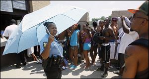 Toledo Police Officer Burna Guy tries to keep tempers cool at Willys Park when she told about 50 people the pool was at capacity.