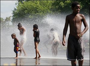 Children cool off in a fire hydrant at Walnut Street and Michigan Street. City officials urged residents not to open the hydrants. 