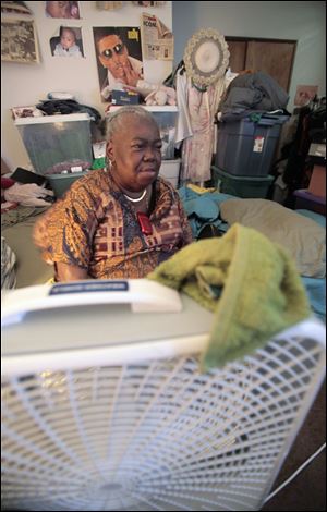 Mary Ware of Chicago, who says she can't afford air conditioning, waits for a ride in front of a fan. 