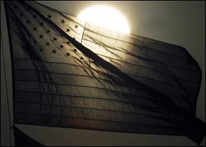 The sun sets behind an American flag Thursday in Lawrence, Kan..