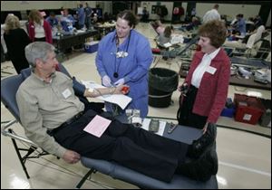 Red Cross Blood Drive chairman Bill Thome talks to Red Cross worker Heidi Keppinger as he gives one pint of blood at the drive at St. Patrick of Heatherdowns Church in January. 