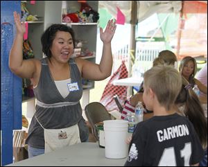 Cindy Brown of West Toledo celebrates as Keera Garmon, 7, obscured by her brother Kellen, 9, wins a goldfish.