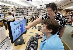 Kathy Fink of Maumee, who suffered severe loss of vision after eye surgery in 2003, uses the low-vision computer station at the Holland branch library as directed by branch manager Linda Kerul.