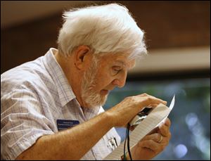 Paul Rachow, one of the six organizers of the support group in 2005, uses a magnifier to study his notes for the meeting at the Holland branch library.