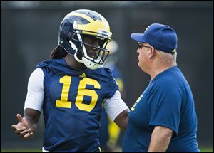 Michigan quarterback Denard Robinson, left, talks to offensive  coordinator Al Borges during practice. Borges top goal right now is to establish a running game for UM.