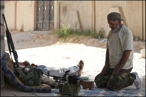 A Libyan rebel prays with his weapons in the town of Zawiya, roughly 50 km (30 miles) west of Tripoli, Libya, Tuesday, Aug. 16, 2011. The day Libyan rebels advanced into the strategic city of Zawiya, Moammar Gadhafi's forces clamped down on the local hospital. They forced doctors to perform hours of consecutive surgeries, put snipers on the roof and an anti-aircraft gun near the entrance, two doctors who managed to escape said Tuesday.