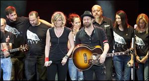 Surrounded by their tour crew, Sugarland duo Jennifer Nettles, middle left, and Kristian Bush, middle right, react after performing their song 