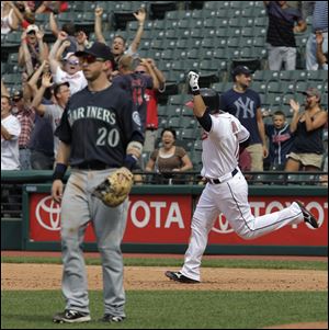 Seattle Mariners left fielder Mike Carp walks from the field as Cleveland Indians Shin-Soo Choo, of South Korea, rounds the bases after hitting a three-run walk off home run in the ninth inning to give the Indians a 7-5 win over the Seattle Mariners in the first  baseball game of a doubleheader in Cleveland on Tuesday, Aug. 23, 2011.