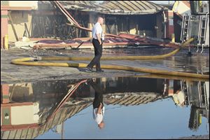 Gary Martin, deputy chief of operations for the Toledo Fire Department, walks past a burned-out Platinum Showgirls on Tuesday morning as Toledo firefighters pour water on smoldering embers at the strip club and surrounding businesses.