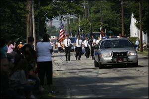 The parade featuring area veterans groups, Northwood High School marching band, and police and fire units travels past spectators.