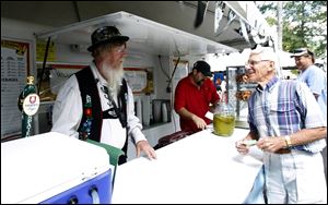 Customer Joe Liebrecht of Delphos, Ohio, right, gives Toledoan Terry Weaver, left, his order for a cold one. On tap were Warsteiner, Spaten, and Lowenbrau.