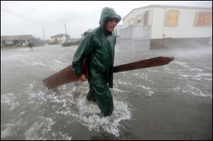 Chris Swimm retrieves planks from a friend's deck that was washed away by waves from the storm in Fairhaven, Mass.