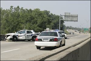 Toledo Police investigate the scene of a cruiser crash that happened Saturday morning on I-75 south, near Exit 206 for Phillips Avenue, during a chase of a man wanted in an armed robbery.