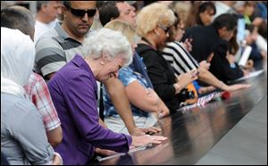 A woman weeps over a name inscribed on the edge of the north pool at the National September 11 Memorial in New York City. The memorial was opened Sunday only for relatives of the terrorist attack victims.