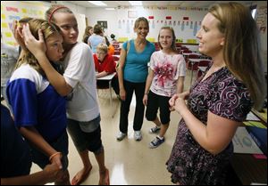 Colleen Kriston, 13, is consoled by her friend Maddy Hessel, 13, after learning about a homework assignment from eighth grade math teacher Kristy Shoemaker, right.