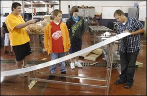 Whitmer students from left Austin Shaffer, 15, Paul Kasten, 15, John Wilkes, 14, and Steven Yates, 14, inspect their completed track for the Pinewood Derby.