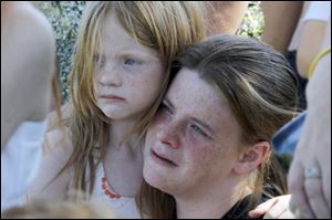 Nellie Flippo, right, reacts to a speech made by Tanya Zuvers while holding her daughter Claudia Flippo, left, who was friends with Alex Skelton, during a prayer vigil in Morenci's Wakefield Park near the three trees that were planted in honor of the Skelton brothers, Andrew, 9, Alexander, 7, and Tanner, 5, who have been missing since last Thanksgiving Day.  