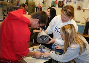 Orchard Center High School art teacher Melissa Smith, center, and student Boston Dussia, left, and Veronica Marsh put the head on their pumpkin entry in the pumpkin design contest. 