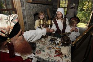 Elliot MacFarlane gives historical coins to 'children of English soldiers' during the Revolutionary War encampment at the Wood County Historical Center in Bowling Green. The children are, from left, Elyse McMaster, 10, Elliot McMaster, 3, Swanton resident Shelby Brooks, 10, and Claire McMaster, 7. McMaster siblings are from Liberty Center.