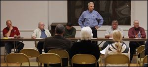 Mayor Lowell Krumnow, left, and his brother James, a councilman, are at opposite ends of the table as Doug Perkins addresses a forum.