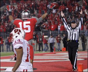 Ohio State's Devin Smith (15) celebrates his game-winning touchdown against Wisconsin's Marcus Cromartie during the fourth quarter of an NCAA college football game Saturday, in Columbus, Ohio. Ohio State beat Wisconsin 33-29. 