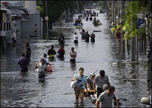 Thai residents carry their belongings through flood waters in October as they move to higher ground at Bangkok's Don Muang district, Thailand. 