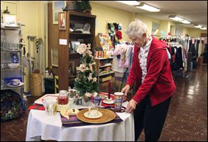 Ruth Arnot, a volunteer in The Giving Store, arranges a holiday display. Everything is free in the store in the basement of Glenwood Lutheran Church beside the Toledo Museum of Art on Monroe Street.