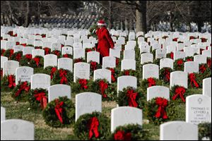 Volunteer Pati Redmond of Frederick, Md., helps to lay more than 100,000 holiday wreaths over the white tombstones at Arlington National Cemetery during Wreaths Across America Day. 