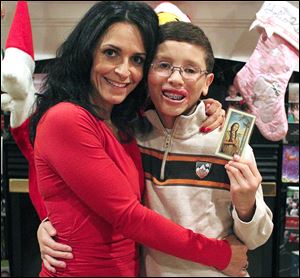 Elsa Finkbonner hugs her son, Jake, who holds a picture of Blessed Kateri, patroness of American Indians, credited with his recovery.