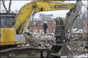 A handler with a cadaver dog searches the rubble for Delano ‘Red’ Fleming as an excavator waits to clear more debris. Two dogs were used at the site Saturday, and they combed it several times during the recovery effort.