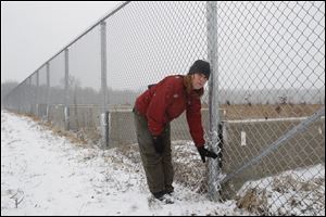 Betsy Yankowiak, Director of Preserves and Programs for the Little River Wetland Project, shows how high a water level got on the Asian Carp barrier fence at Eagle Marsh near Fort Wayne, Indiana, Thursday.