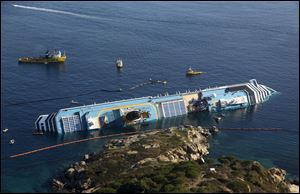 The Costa Concordia cruise ship lies on its side, off the tiny Giglio island, Italy. Italian officials say Monday two more bodies have been pulled from the wreckage of a the cruise liner bringing the number of confirmed dead to 15.