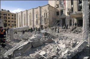 Syrian security forces walk on the wreckage of a damaged building at a security compound that was attacked Friday by an explosion, in the northern city of Aleppo, Syria.