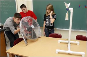 Julio Mata, 12, from left Robby Edwards, 12, and Andrea Lee, 12, experiment with a model turbine they built in their seventh grade science class at  Eisenhower Middle School in Oregon, Ohio.