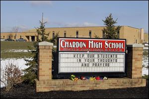 Bouquets of flowers sit on the sign in front of the high school in ChardonTuesday. A gunman opened fire inside the school's cafeteria at the start of the school day Monday, killing three students and injuring two more.