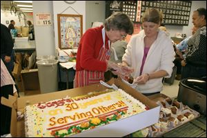 Marge Kirkhope, left,  and Teresa Ferner cut the cake for the meal as the Hospitality Kitchen at Our Lady of Lourdes marks 30 years of helping people in need.