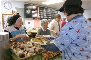 Louise Beauregard, right, is served lunch Wednesday by Sister 'Cupcake' Felicitas, left, and Phyllis Senecal at the Hospitality Kitchen in the Parish Hall of Our Lady of Lourdes on Hill Avenue in Toledo.