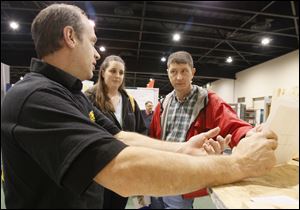 Dan Schmitt, left, speaks with Mae and Tony Dryer of Adrian about spray-foam insulation. Sasha Andreev of HGTV’s ‘Curb Appeal’ is to speak with show-goers from 11 a.m. to 2 p.m. Sunday.