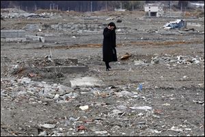 A woman stands in an area devastated by the March 11, 2011 earthquake and tsunami, in Minamisanriku, Miyagi Prefecture, Sunday.