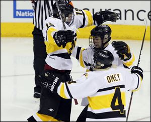 Northview's Drew Crandall (15) jumps on teammates Kyler Omey (4) and Dalton Carter (25) after scoring a goal against Lakewood St. Edward during the state hockey championship game.