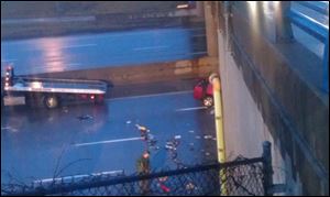 A worker tries to clean up some of the debris on I-75 southbound after the early morning crash Monday.