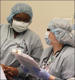 Justina Onwughala, left, a certified registered nurse anesthetist, confers with anesthesia aide student Sarah Crim during Dr. Todd Monroe’s surgery.