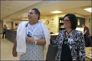 Dr. Todd Monroe and nurse Kristi Weber greet one of Dr. Monroe’s heart patients as he walks the halls at ProMedica St. Luke’s Hospital in Maumee. The strap around Dr. Monroe’s chest is used for support and to ease his pain.