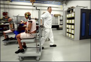 A vehicle safety specialist at the Honda facility retrieves an anthropomorphic test device, better known as a crash-test dummy, for a test at the crash-simulation lab. The devices are built to look like men, women, and children of various sizes and shapes.