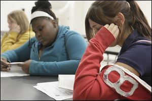 Miya Townsend, 13, left, follows along in 'The Glass Castle' as Julissa Ornelas, 13, reads the bestselling novel aloud at Adelante Inc.  