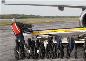 Jeff Stephenson, fixed base operations manager for Grande Air, loads wheelchairs onto a luggage conveyor prior to the first Honor Flight Northwest Ohio of 2012 April 25 at Toledo Express Airport. The flight carried 74 World War II veterans to Washington.