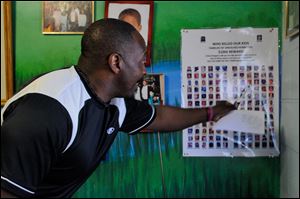 The Rev. Peterson Mingo, a street advocate for the Cincinnati Initiative to Reduce Violence, points to a family member on a poster of homicide victims in his office. Mingo served time in state prison for robbery.