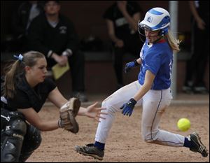 Springfield's Ashley Zappone scores as Perrysburg catcher Kimmy Granata awaits the throw in the sixth inning. The Blue Devils (22-1) clinched at least a share of their second NLL crown in the last four seasons, also winning in 2009.