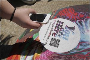 A Toledo School for the Arts student uses her QR code app to scan the dot in front of the school building.