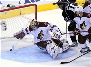 Phoenix Coyotes goalie Mike Smith, left, deflects a shot as Los Angeles Kings center Anze Kopitar, center, and defenseman Derek Morris during the third period of Game 3.